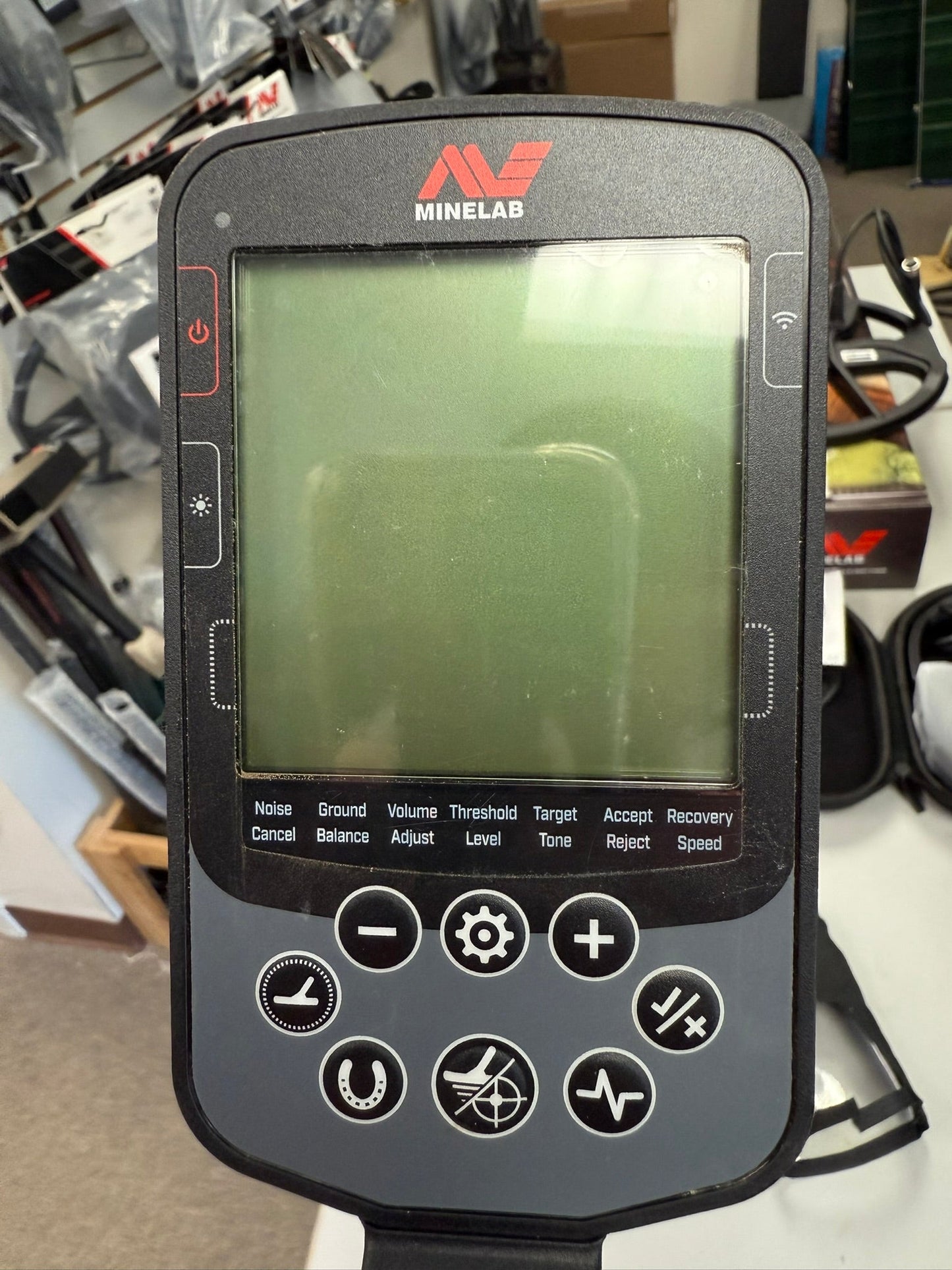 Minelab metal detector with screen and control buttons on a blurred background